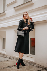 a lady in a black top, a black skirt and a black crop jacket